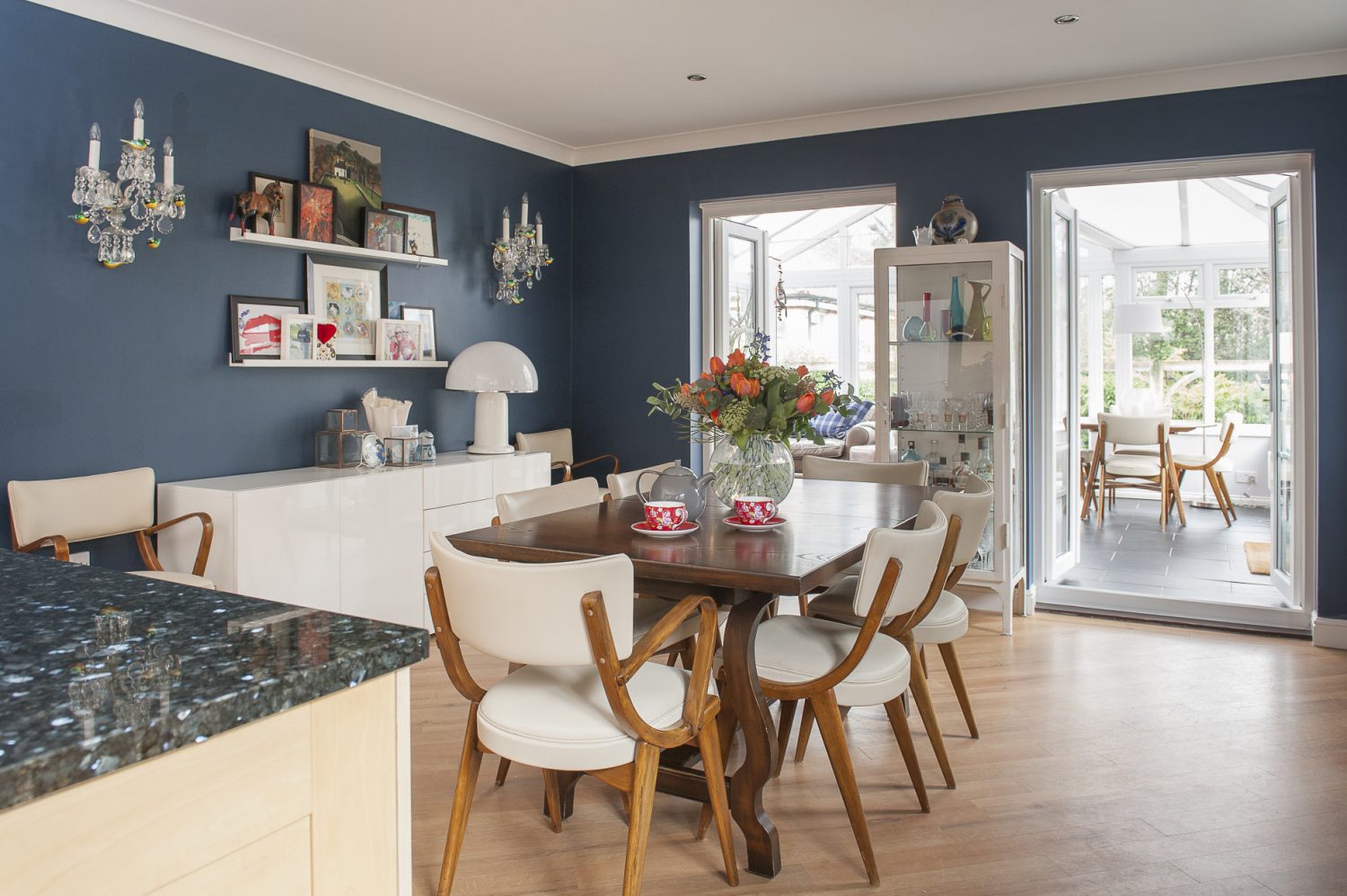 The open plan kitchen and dining room is painted a rich, deep blue