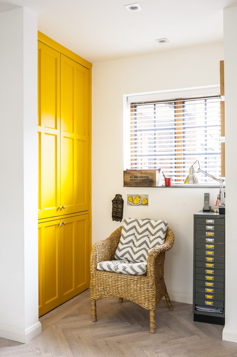 The ‘simple yellow’ of the Tesco bar stools in the kitchen is echoed by lamps in the living room and the painted doors of a downstairs storage cupboard.