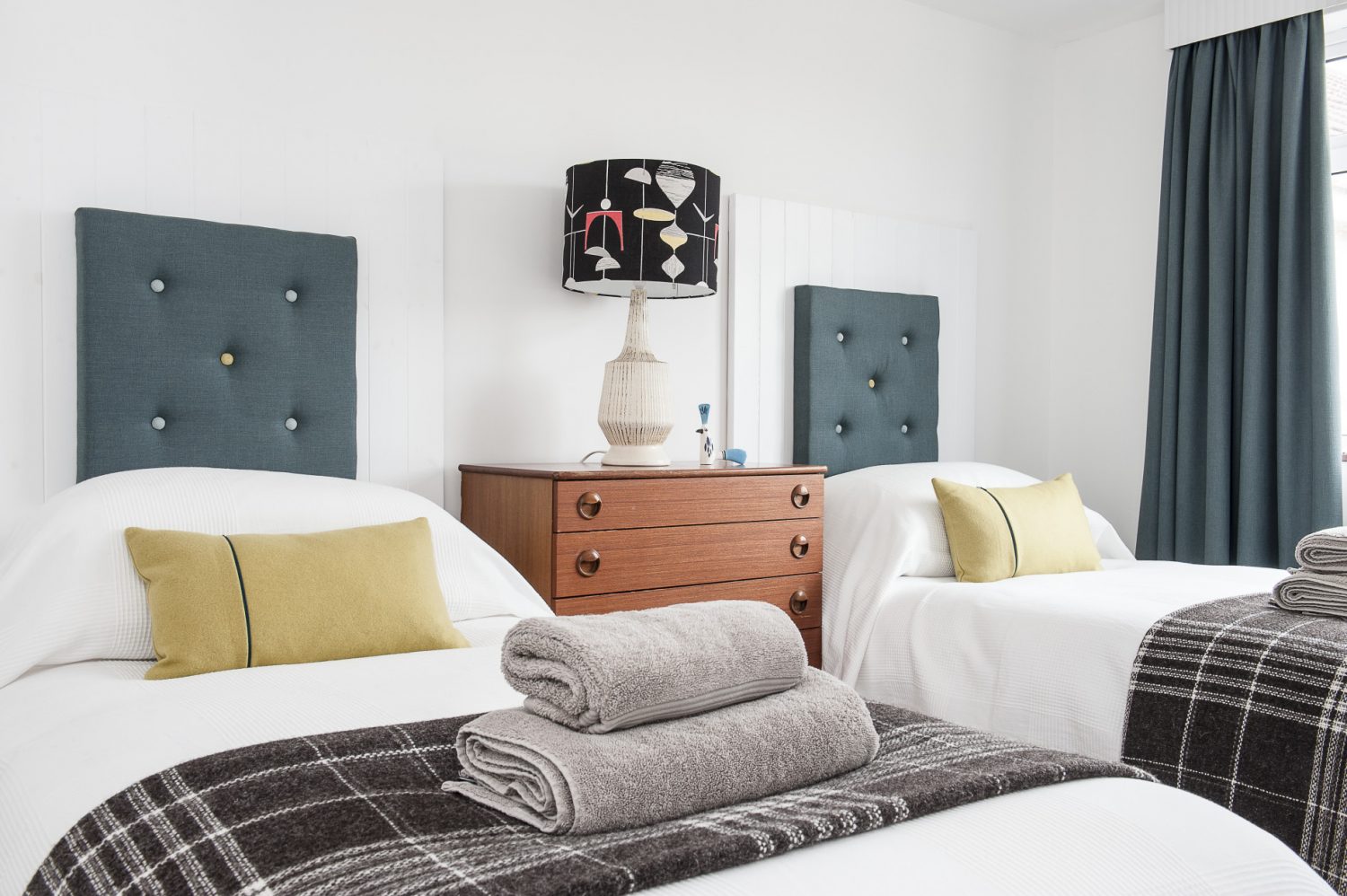 A third bedroom is nestled on the ground floor. James has once again employed his creative skills to make painted wooden headboards onto which he has mounted upholstered squares. A trio of framed album covers are mounted onto one wall