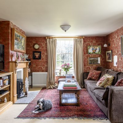 The sitting room exudes warmth and comfort with a palette of rich reds and squashy sofas