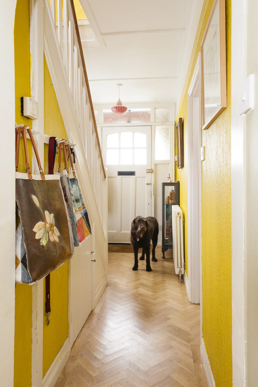 Hand-painted canvas bags from John and Anna’s latest project hang from hooks in the hallway