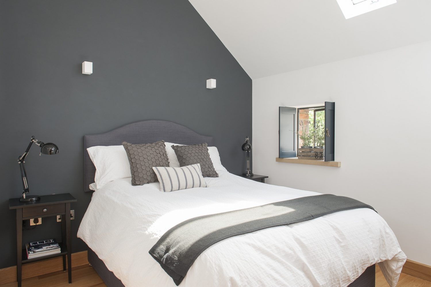 The second guest room, painted a deep grey, is a pleasing combination of contemporary minimalism with a dash of country charm – the latter provided by a pretty shuttered window