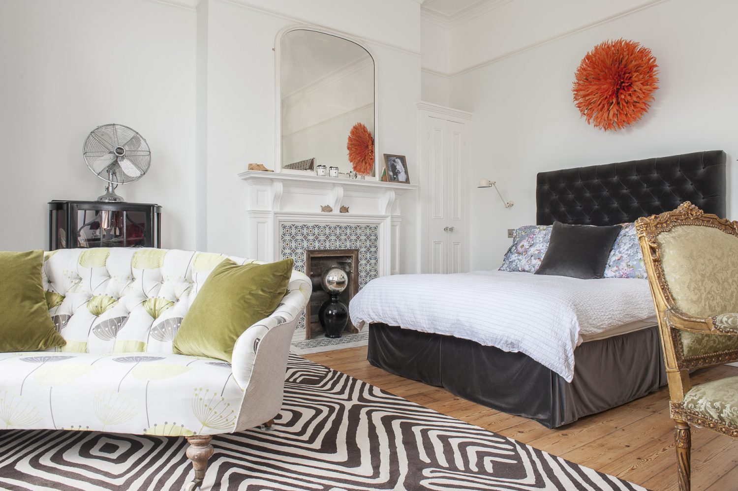 The fireplace in the couple’s master bedroom has been stripped of paint and returned to its former glory. The velvet button backed headboard and bed come from sofa.com and the Cameroonian tribal headdress from Sideshow Interiors in St Leonards.