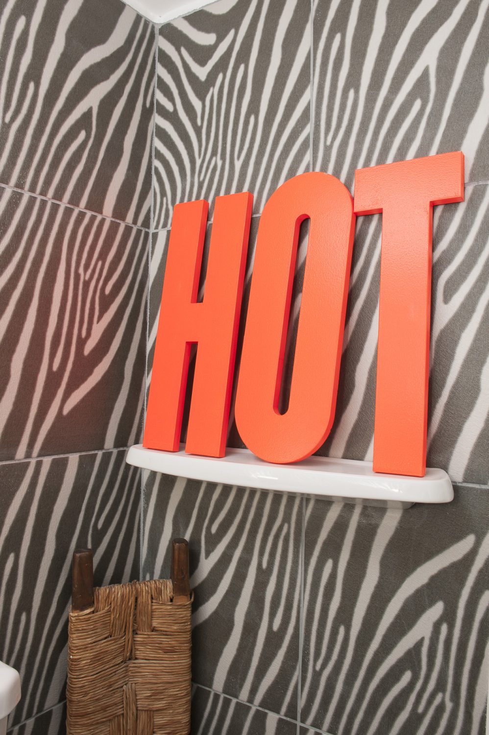 Giant neon ‘HOT’ lettering provides a pleasingly vibrant colour contrast to the monochrome zebra print ceramic tiles