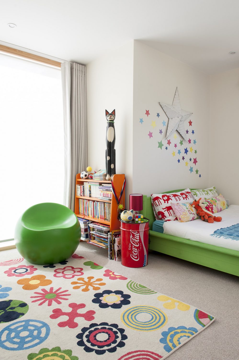 In Jasper’s colourfully accessorised room, Jenny has taken an Ikea pine bed and, with the help of Annie Sloan, turned it lime green to match the 60s ball chair. Beside the bed is a Coca Cola drum table and above it a crowd of multi-coloured stars...