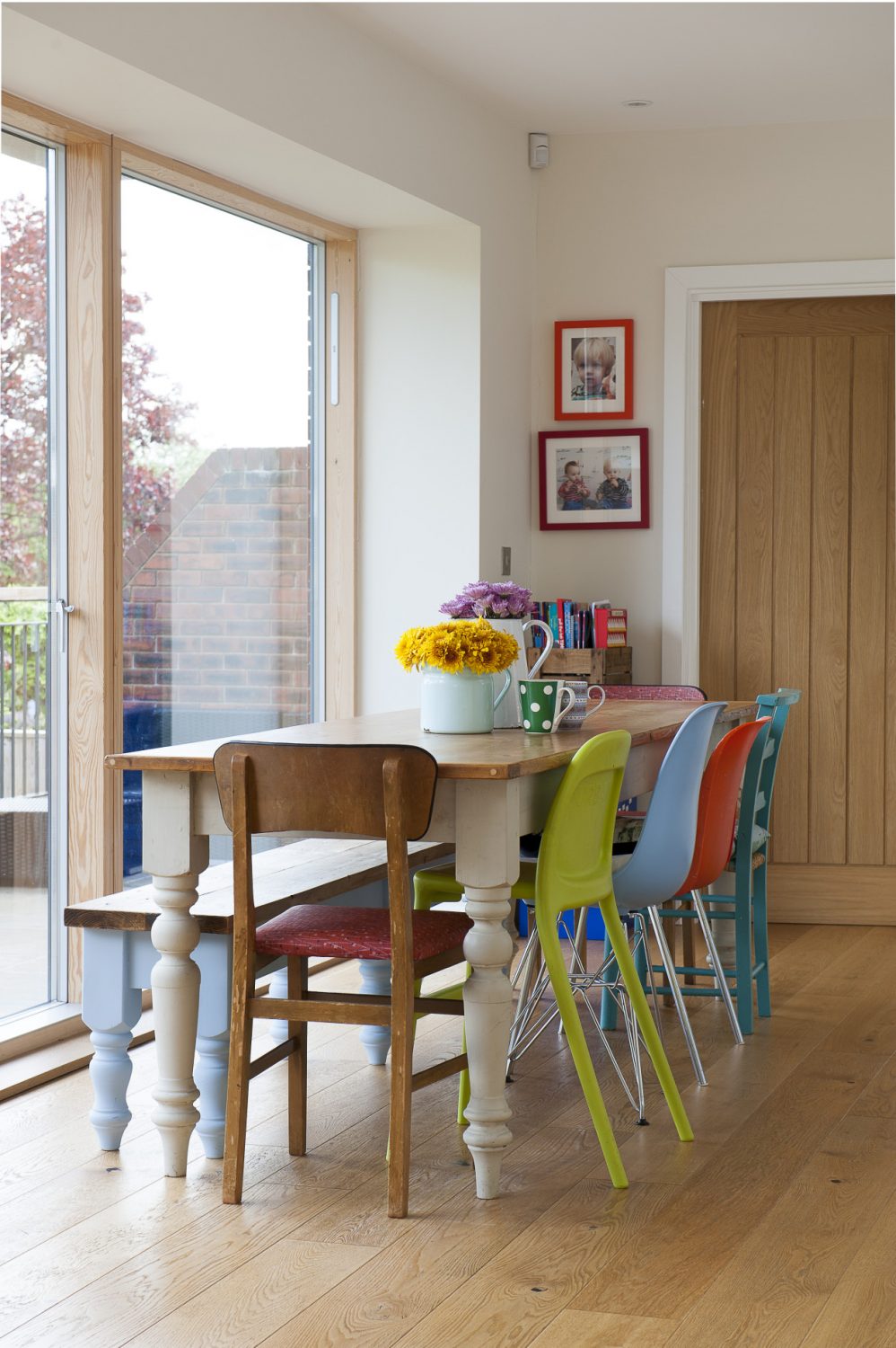 On one side of the pine dining table gather a mix of plastic and metal 1950s/60s and Ikea chairs