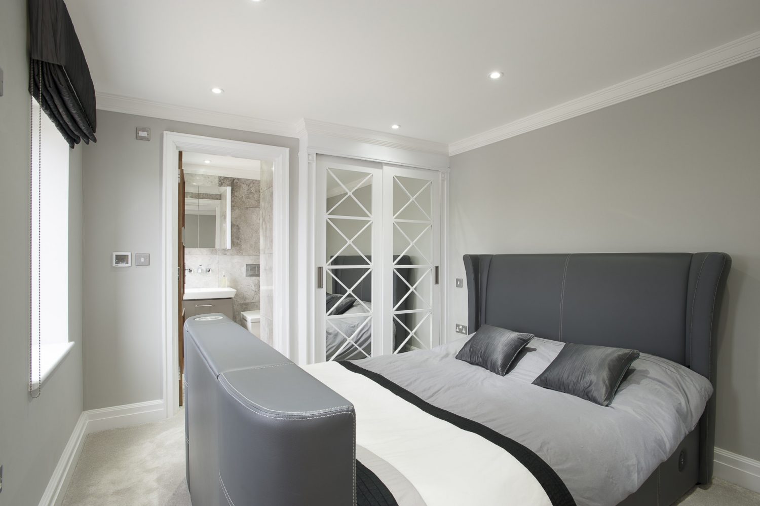 The two guest rooms feature grey leather beds from the feet of which rise flat screen TVs