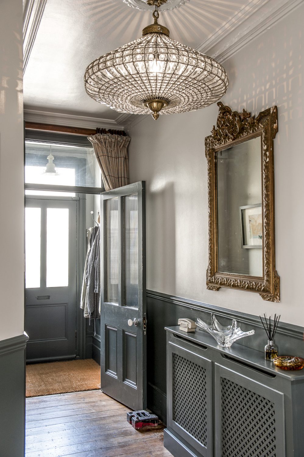 The hallway has been painted a deep shade of grey with accents of gold and sparkling glass provided by the beautifully shaped chandelier, another find from Hastings Antiques Centre
