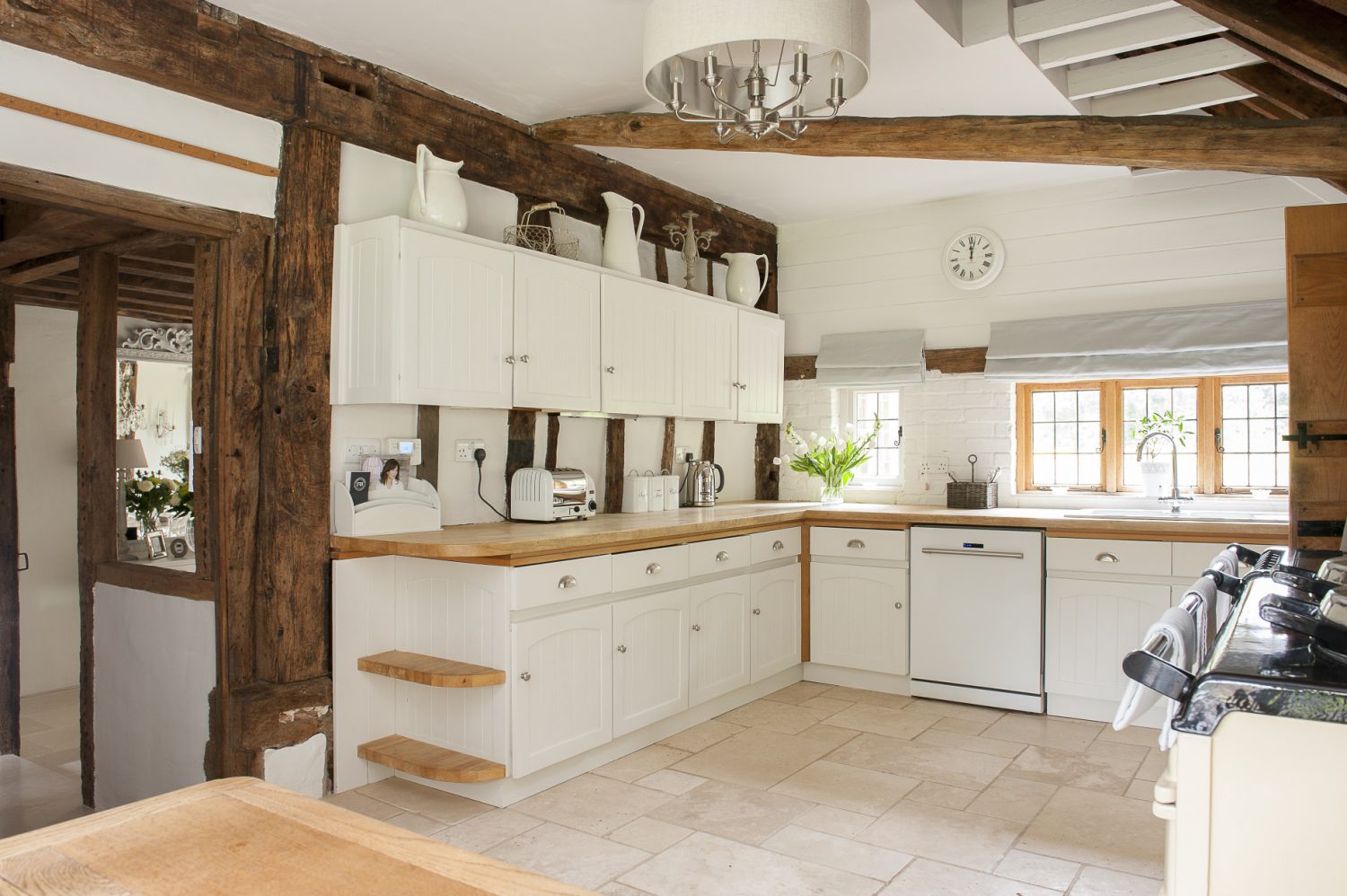 The modern, clean-white kitchen contrasts with the rustic beams and period features of this Wealden farmhouse