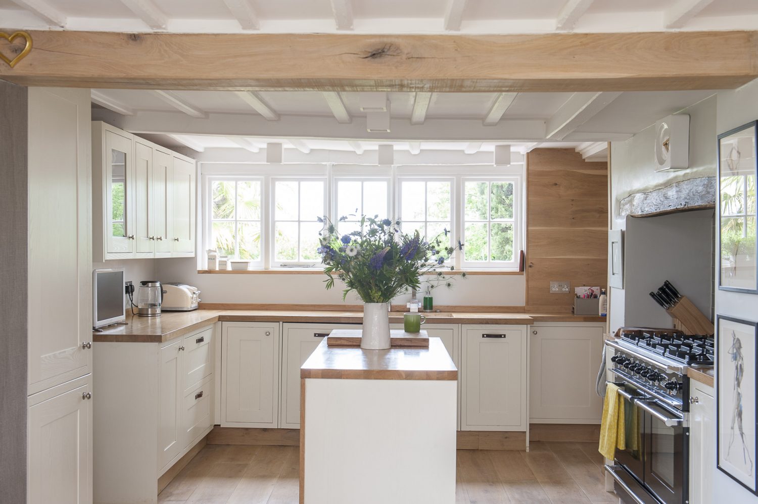 Cream-painted units and pale oak worksurfaces reflect the light