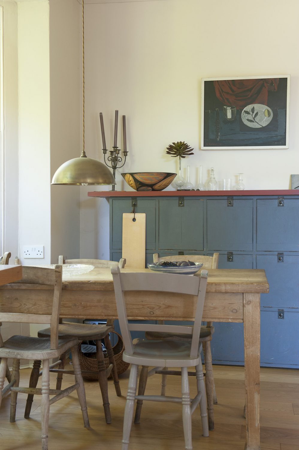 A rustic stripped-wood table sits in the corner of the large kitchen-cum-dining room, with side cupboards painted in a strong blue to complement the colour of the ‘unfitted’ kitchen