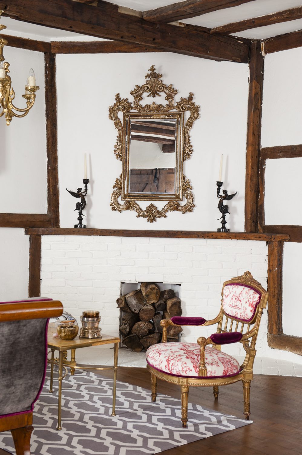 A Venetian rococo mirror is mounted above the painted brickwork of the fireplace