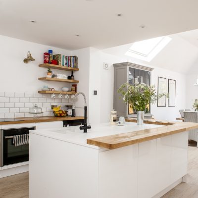 Wood is a recurring theme in the house, softening the all-white kitchen with the wide oak trim around the central island. The copper kettle is from John Lewis and the brass wall lights are from Cox & Cox. The oven is a Neff Slide & Hide, as made famous by Great British Bake Off