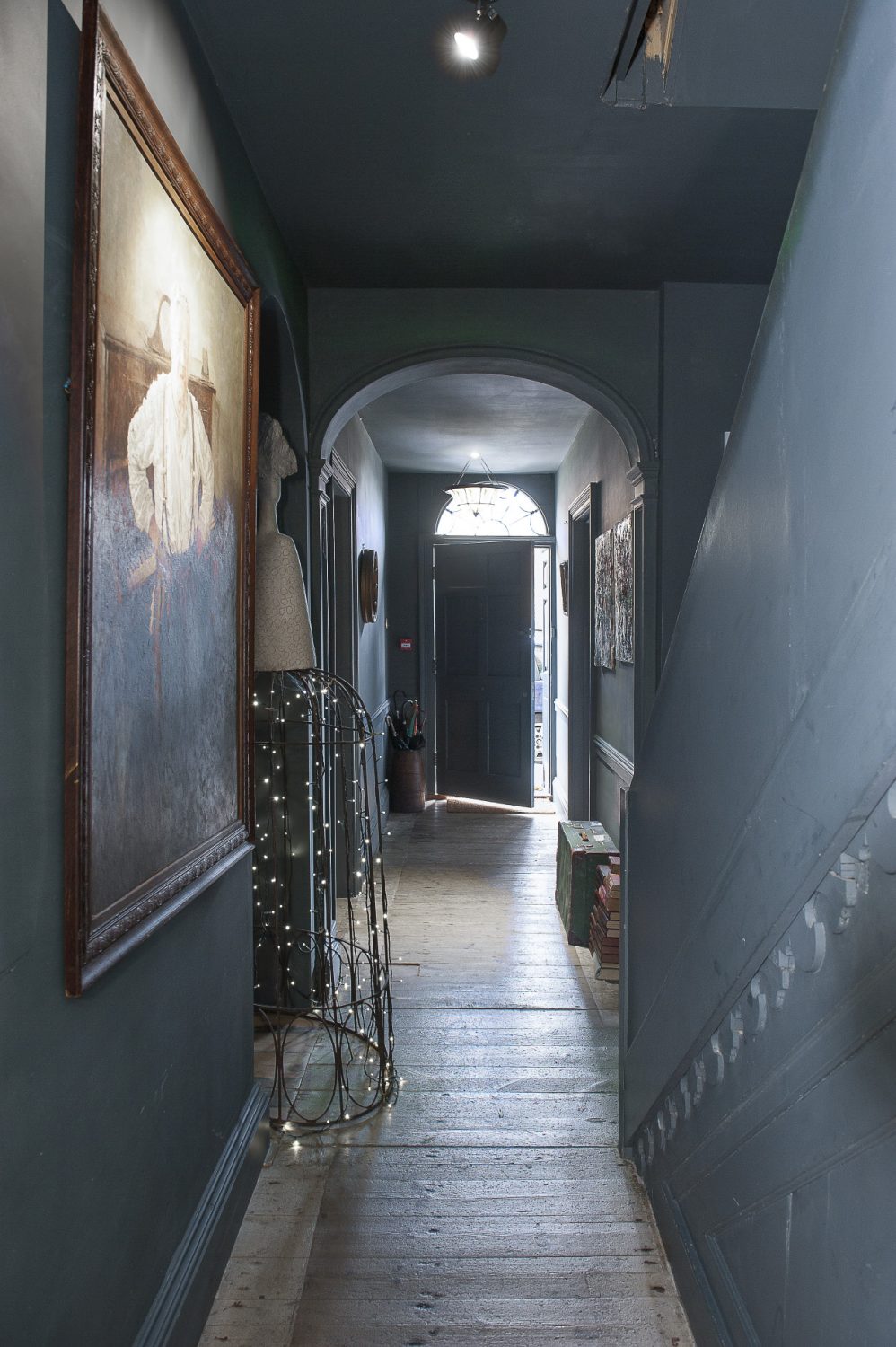 The grey-painted hallway is naturally lit by an original fanlight window above the front door as well as more contemporary fairy lights and spots