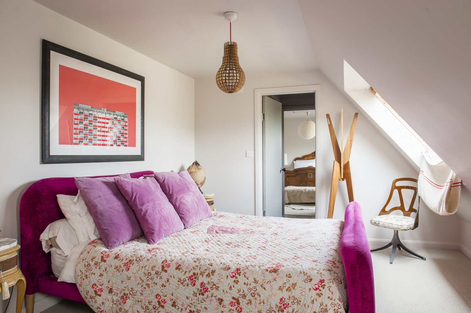 Above the pink velvet bed in the second bedroom is a print of a building in Acton