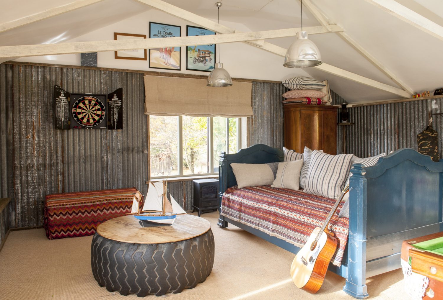 The den’s walls are covered in corrugated iron, which Ally retrieved from various local farmyards, or reclaimed scaffold boards, and a tractor tyre has been topped with planks and turned into a table