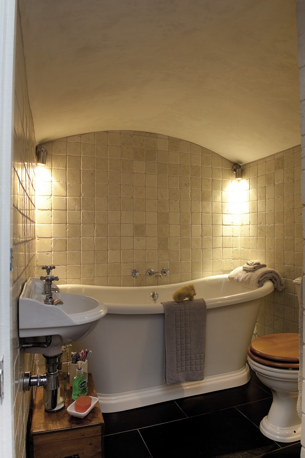 Housed in the former coal chute, the curved ceiling of the bathroom has been retained, so that with the huge freestanding bath and the limestone mosaic tiles, the room has more than a hint of the Roman baths about it.