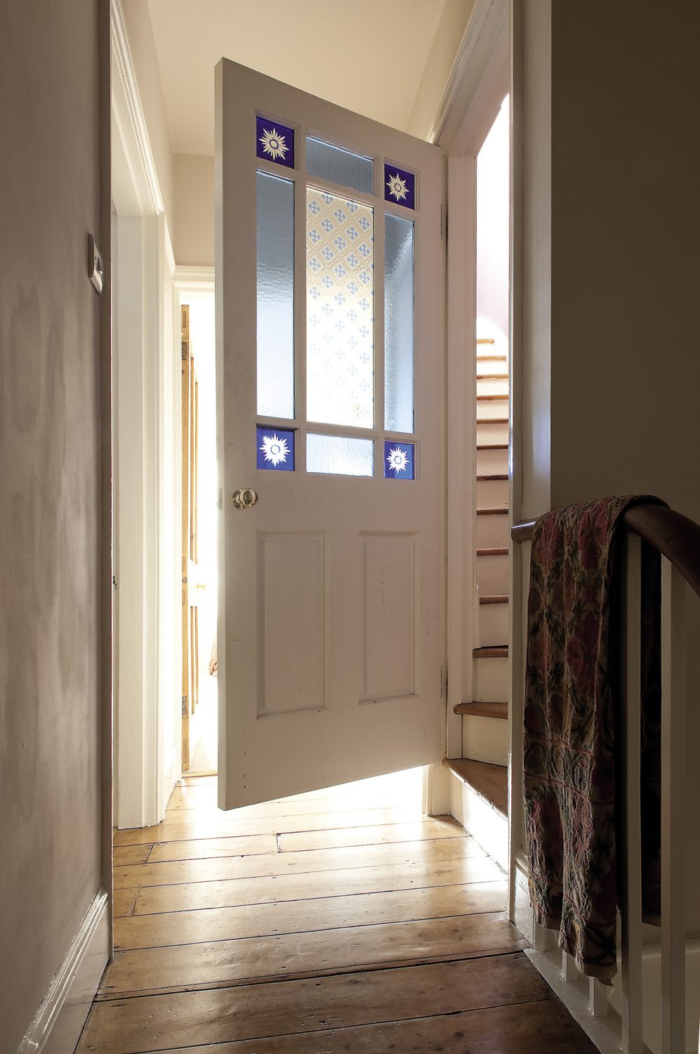 A wooden door with stained glass inserts leads to Bobby’s room on the top floor