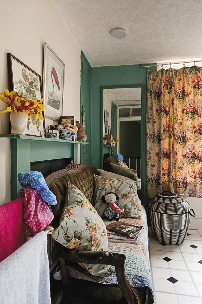 the bathroom sofa is covered with quilted throws and floral cushions