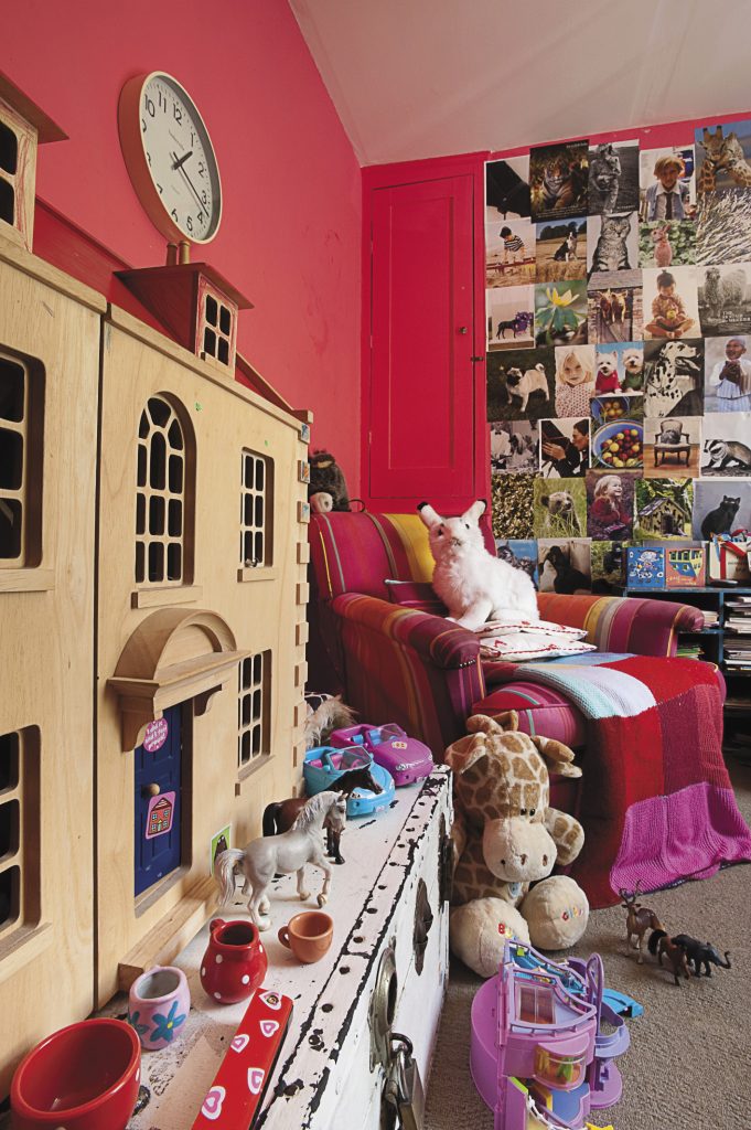 one of the pink playroom walls is papered with favourite pictures