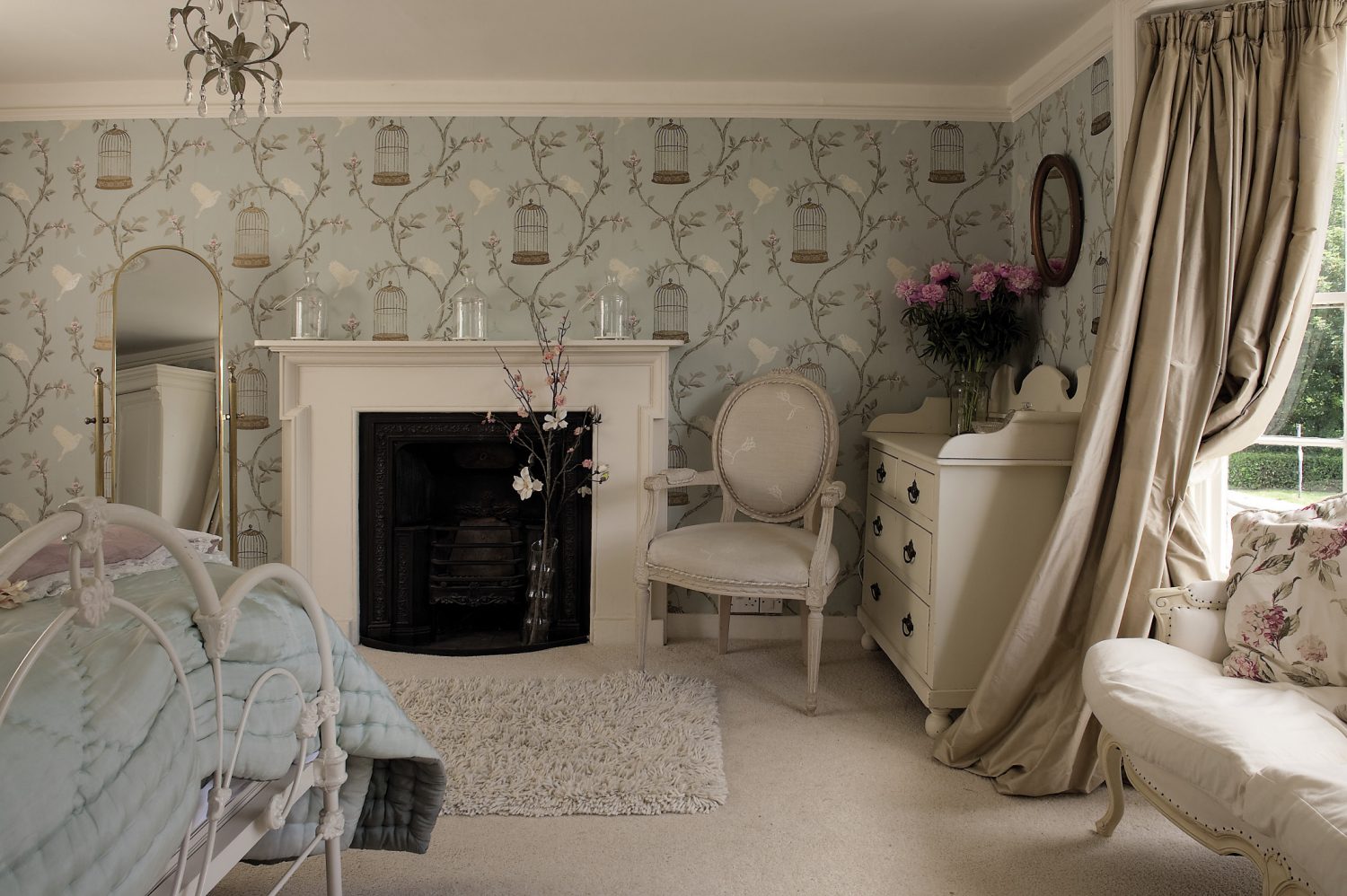 Along the corridor is the ‘Chambre Jolie’, papered in ‘Birdcage Walk’ by Nina Campbell. A French 18th century style sofa occupies the space in the bay window and is framed on either side by café au lait-coloured silk curtains. White painted furniture maintains the feeling of light and the iron bed is dressed with a handstitched eau de nil silk quilt