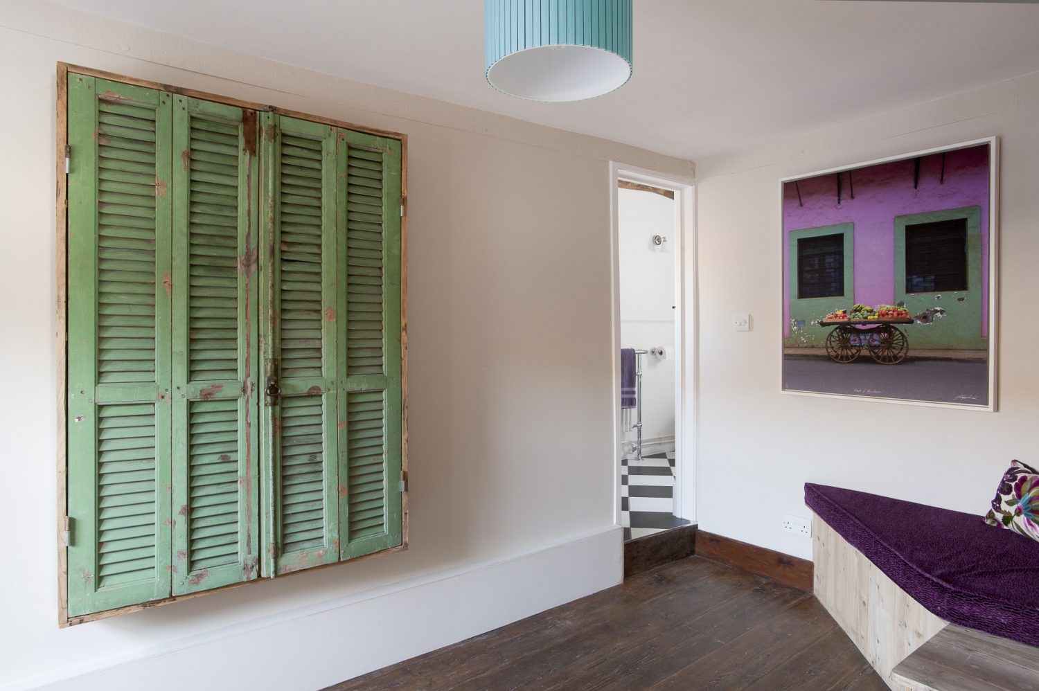 In the study a large photograph printed on canvas echoes the vivid purple and green soft furnishings that Rosemary has used in the room. The bathroom next door features black and white diamond floor tiles, a roll top bath and a Savoy style pedestal basin...