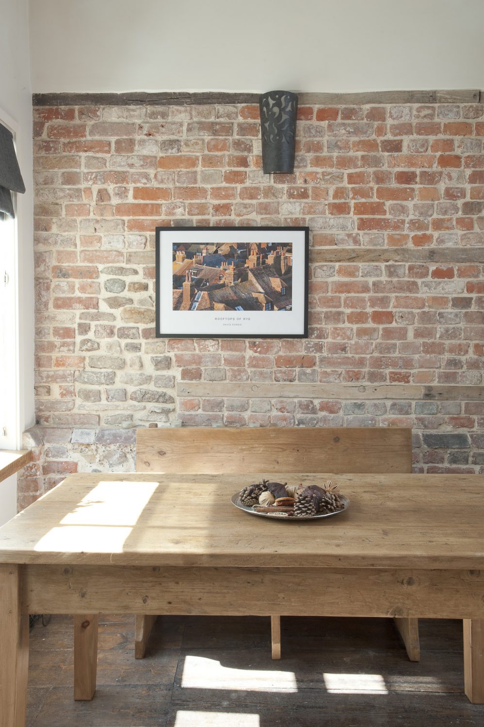 In one corner of the reception room stands a long scrubbed pine refectory table unadorned apart from a bowl of fragrant pine cones and cinnamon sticks. Set against the bare brick wall, it has an honest simplicity.