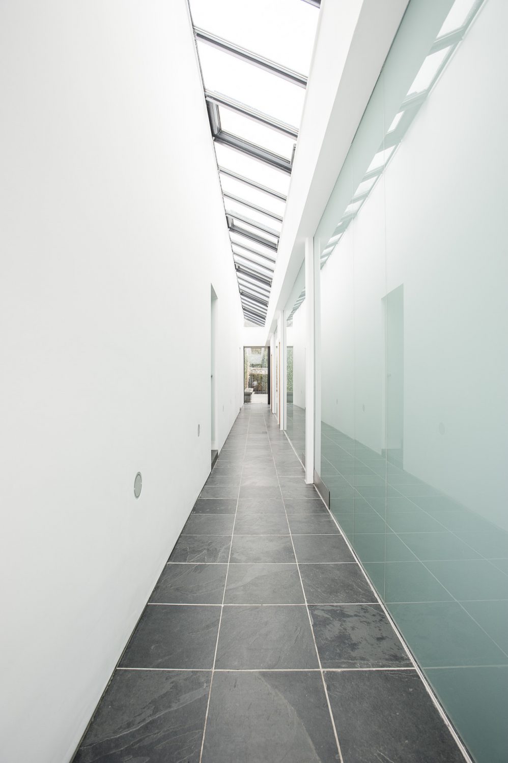 A glazed passageway acts as the spine of the building and separates the contemporary glass part of the building from the original potting sheds