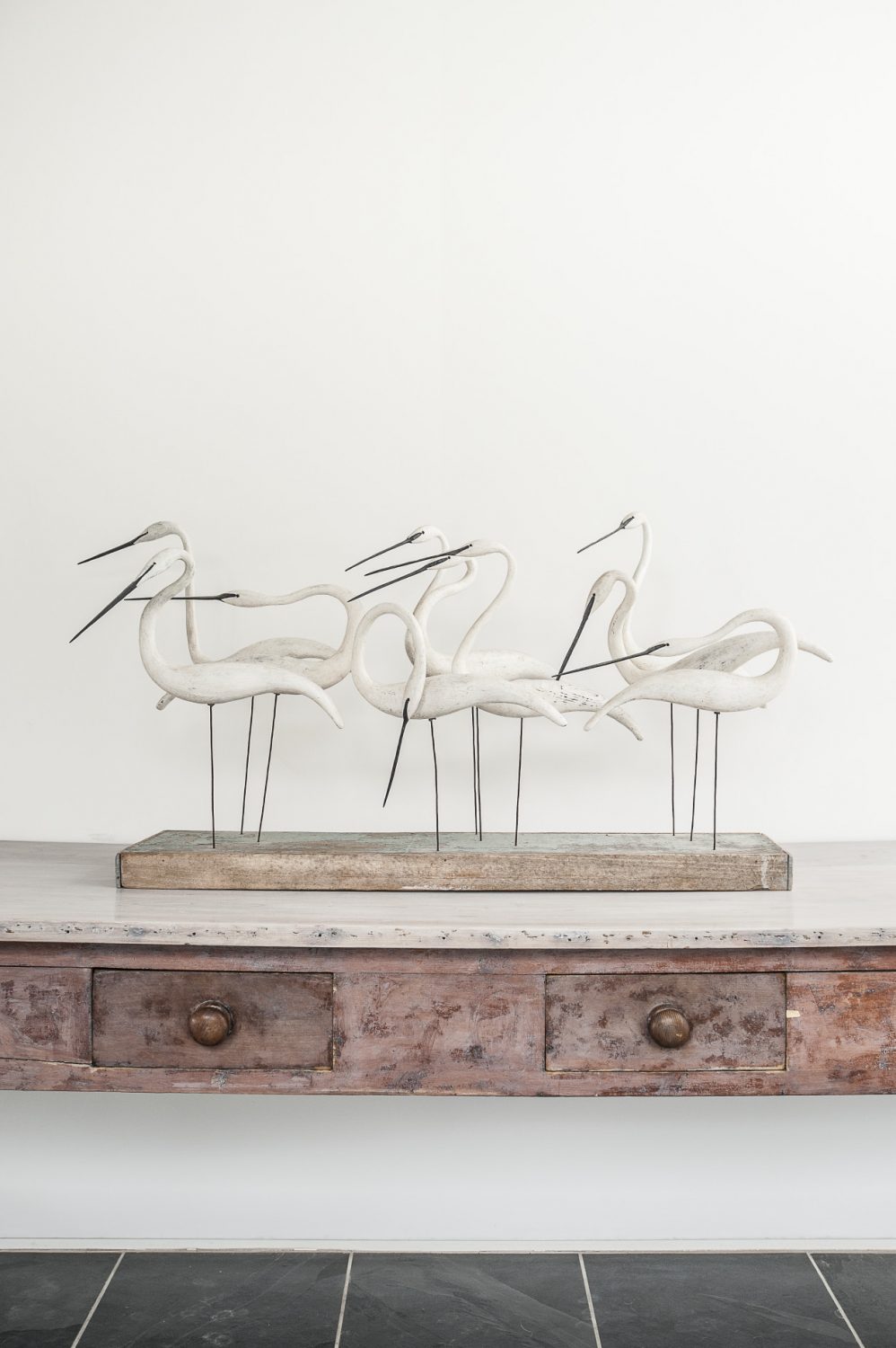 A driftwood sculpture of a group of egrets by Essex artist Guy Taplin stands on a long distressed five-drawer table from a Liverpool convent in the hallway