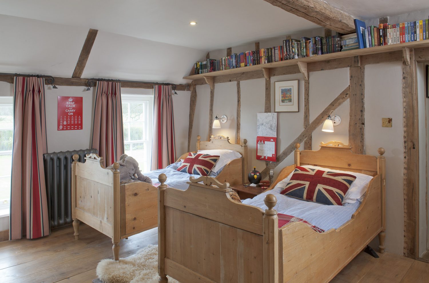 In Oscar’s room, further along the landing, twin pine sleigh beds are covered with blue and white gingham quilts, Union Jack cushions and red and white checked blankets