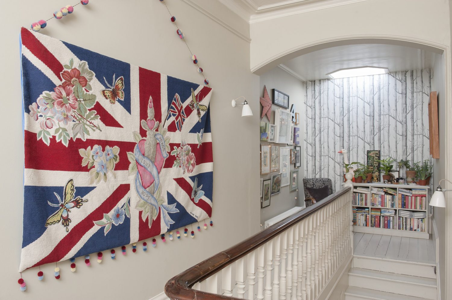 One end of the landing is papered in ‘Woods’ by Cole & Son and looks rather like a forest of bare birch trees. A giant embroidered and beaded Union Jack tapestry hangs boldly on one wall, whilst a comfy armchair is placed next to a set of full-to-bursting bookshelves