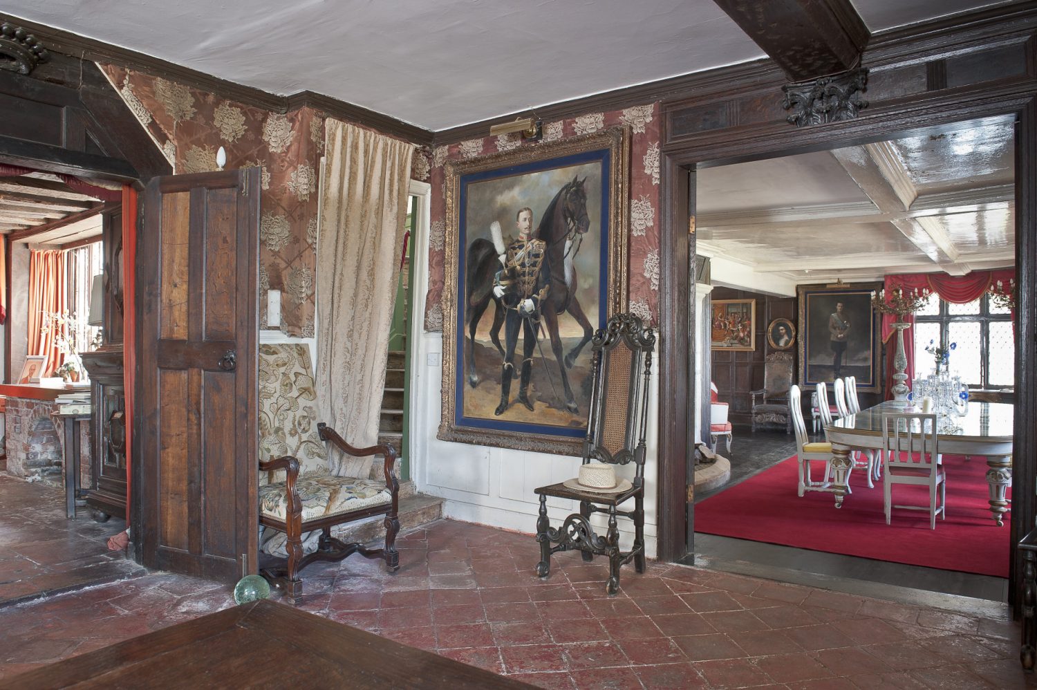 In the reception hall, dark oak timbers criss-cross the ceiling and form carved coronets above double doorways that give access to other parts of the house