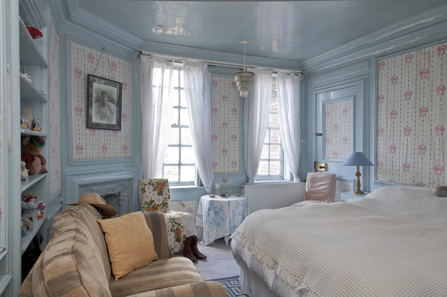 Olga’s old night nursery is an almost perfect capsule of late 19th century interior design, the woodwork on the panelled walls is painted pale powder blue and in between, the wallpaper features tiny yellow rosebuds with pink ribbons running between them