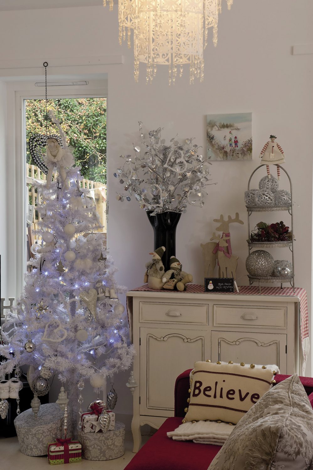 A console table is covered with a red and white gingham runner and a three-tiered sweetmeat stand displays a collection of large baubles as well as a red and white stripy-stockinged peg doll
