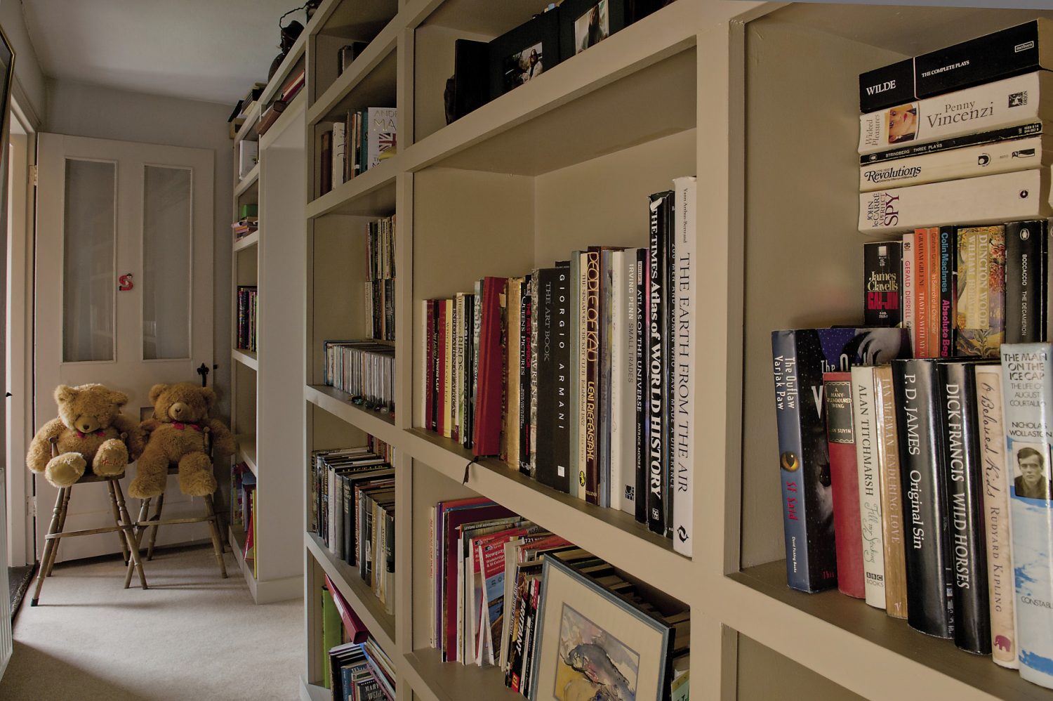 A bookcase groaning with books lines the corridor to one of the children’s bedrooms