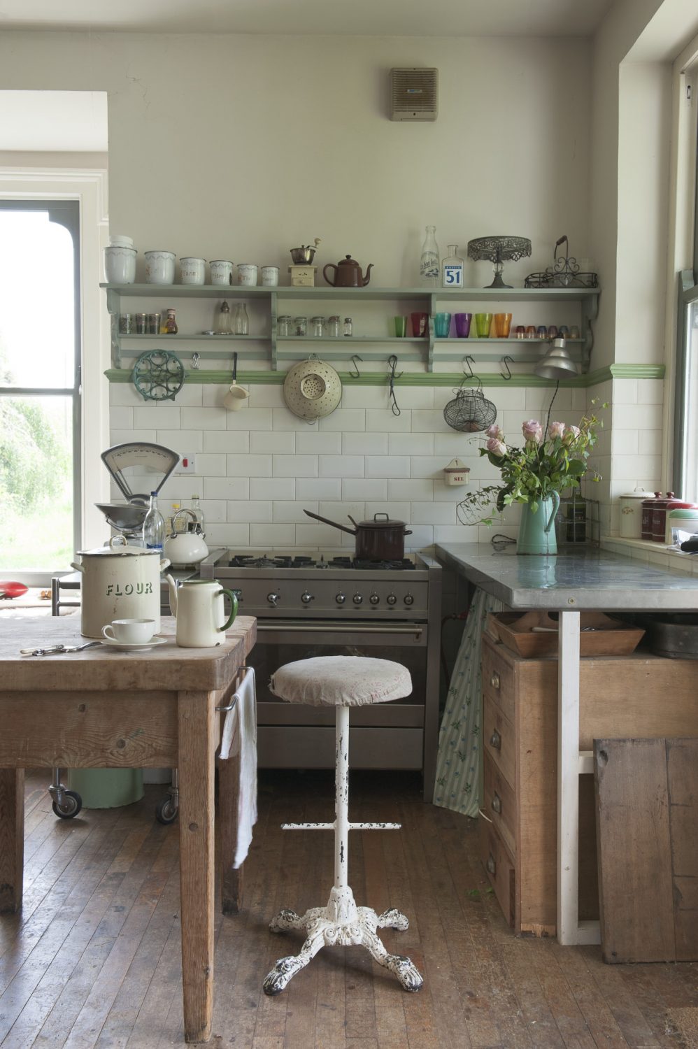 The kitchen is equipped with an assortment of tables and trolleys with under-sink and work surface spaces covered with curtains of cheerful, printed fabrics