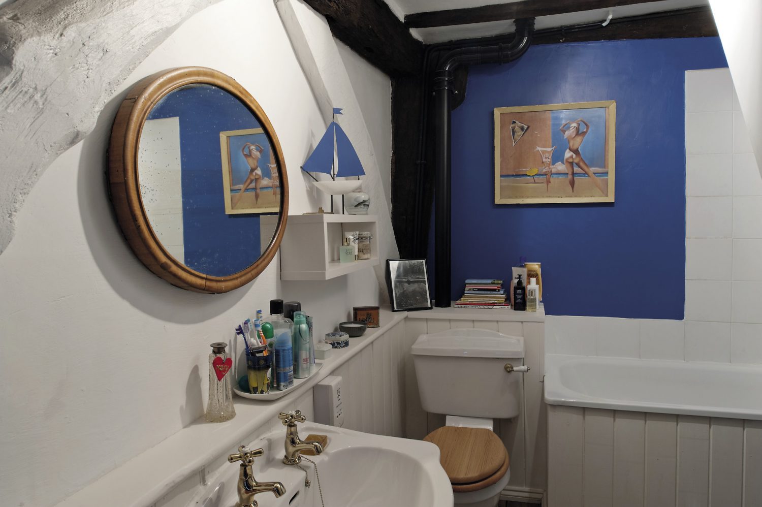 The family bathroom, painted a rich cobalt blue, features artwork collected by David’s father