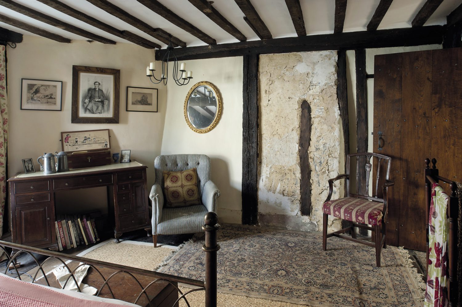 In the guestroom at the front of the house, part of the wallcovering has been scraped away to reveal a panel of pargeting and painting that must date from the 1480s when this house is believed to have been built