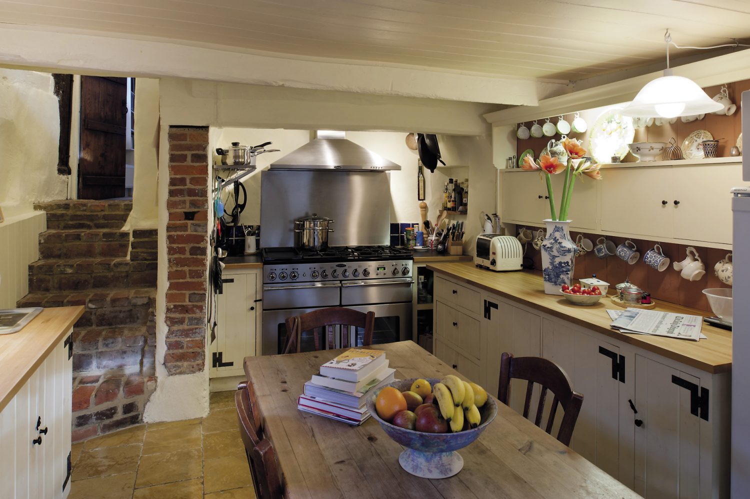Stone steps lead down from the dining room into the kitchen, which was once a scullery. It has been updated with a huge stainless steel range, but has kept its old country charm, with a polished stone floor and scrubbed pine table