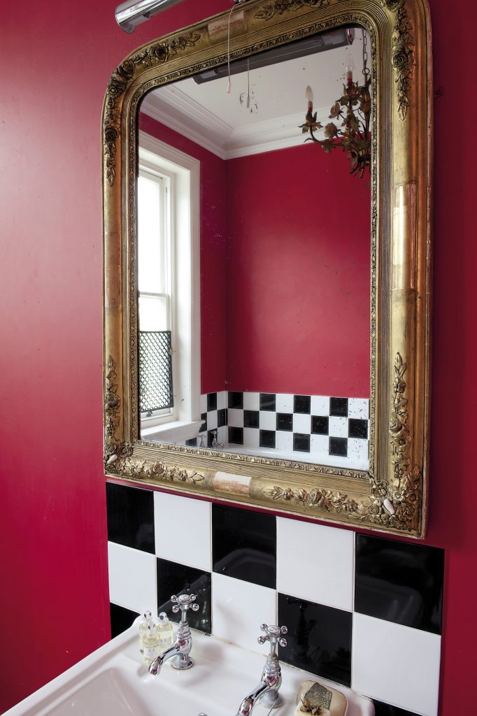 The ‘baroque’ bathroom features bright red walls accented with black and white chequered tiles