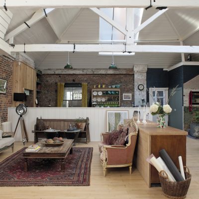 The living room, that also incorporates the kitchen and a dining area, is truly vast, soaring up past huge white-painted beams to the pitched roof. On one side the walls are of bare brick and on the other of age-damaged render