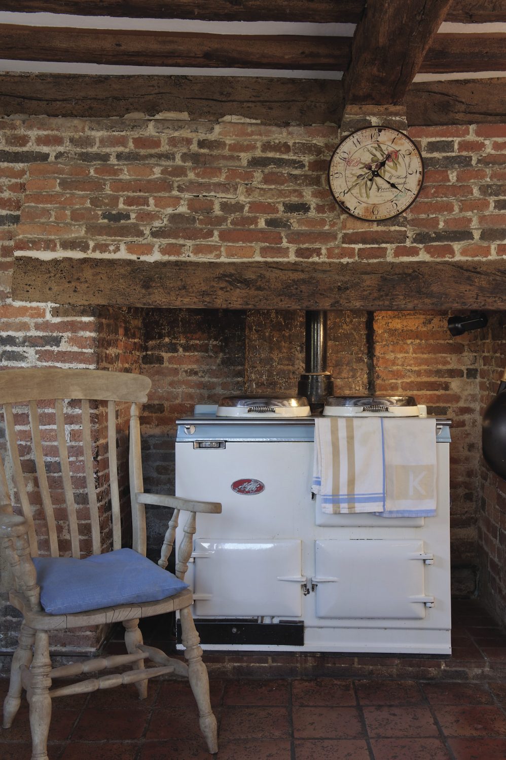 An ivory and duck egg blue Aga occupies the generous brick fireplace