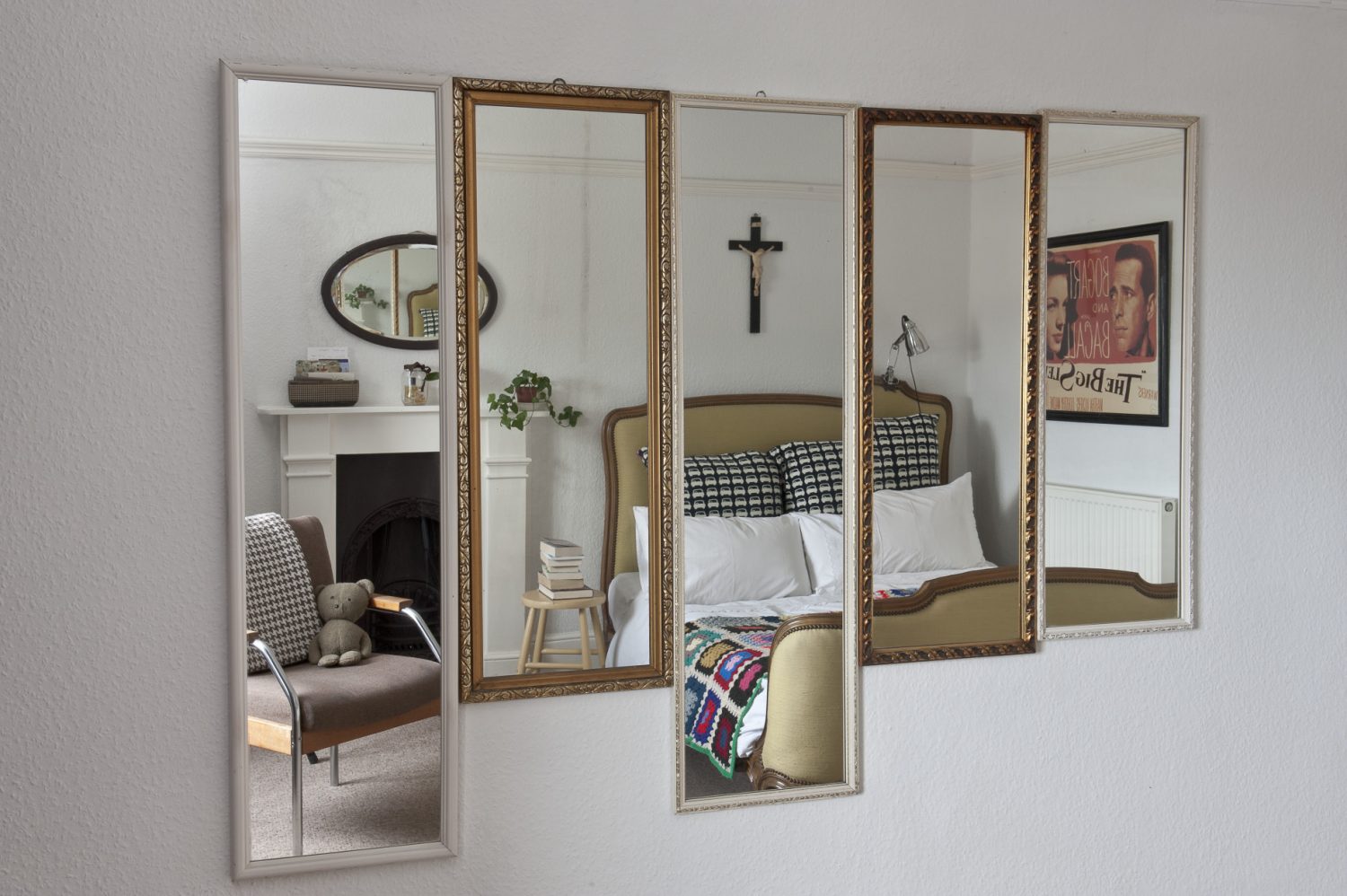 On the wall opposite there is a collection of five framed mirrors, all hung closely together so that they form a kind of panel