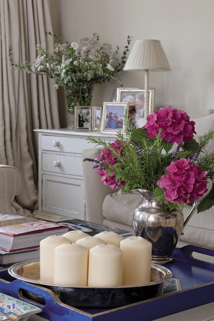 In the drawing room a large square coffee table from Woodcocks in Tenterden shows off neatly arranged piles of art books along with a silver vase filled with hydrangeas and branches of aromatic rosemary