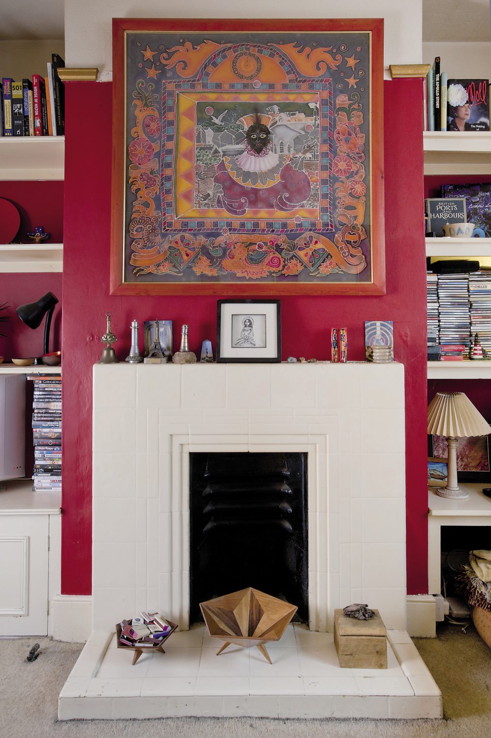 The sitting room is painted a rich, British red with a gold picture rail. Alastair’s love of travel is evident throughout the room, from the oriental rug on the floor to the kilim-style printed fabric that covers the armchair