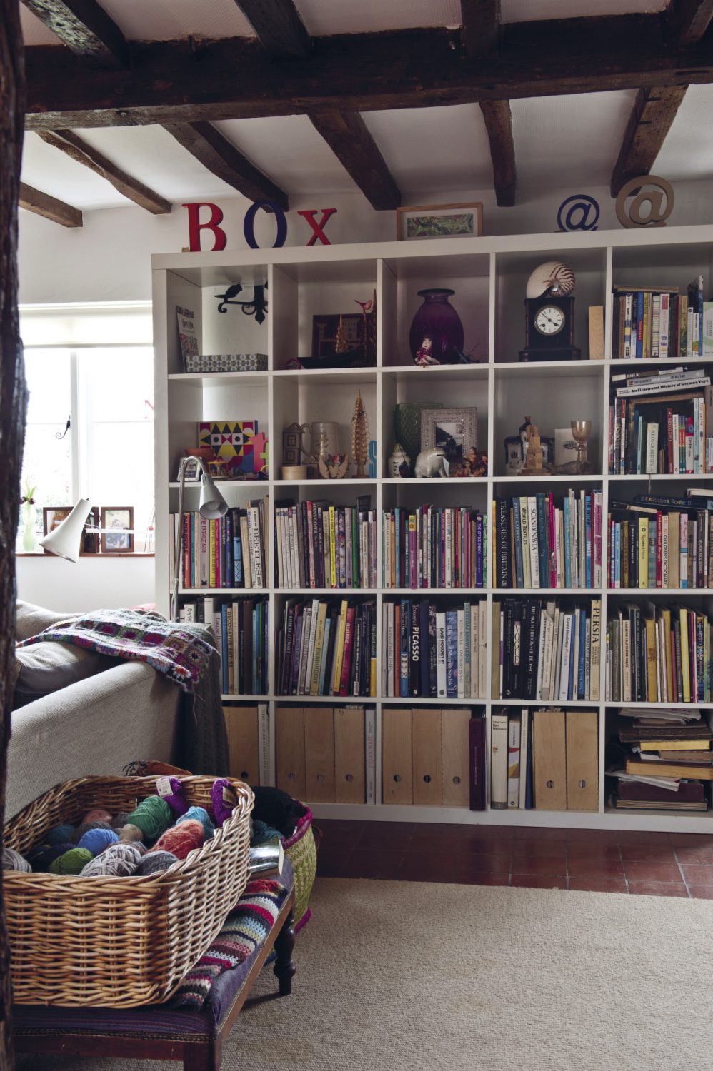 Two sides of the room are covered with shelves with books, files and vintage wooden toys