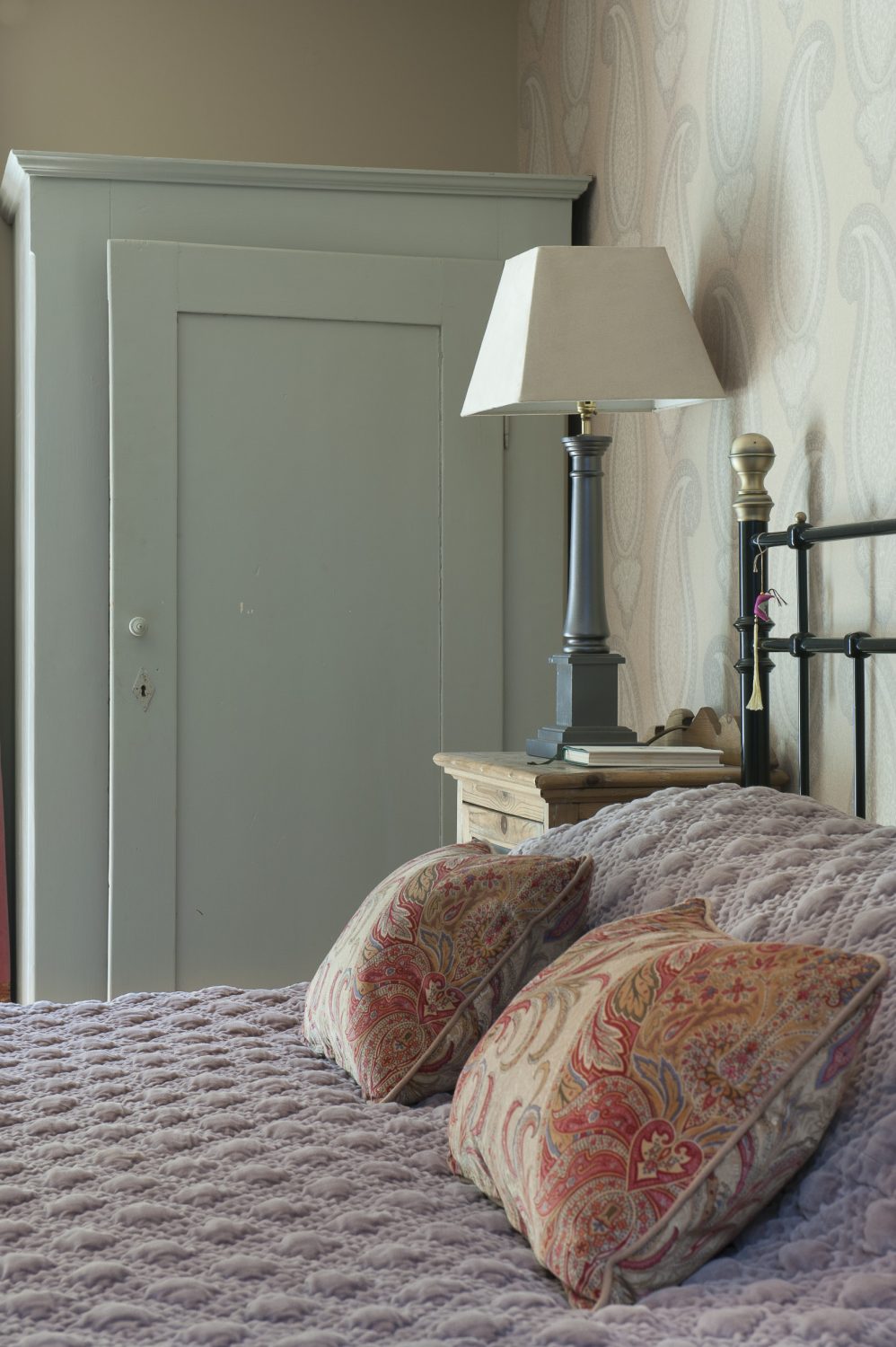 The basement guestroom features a Victorian style brass bedstead and distressed bedside units from Foxhole Antiques