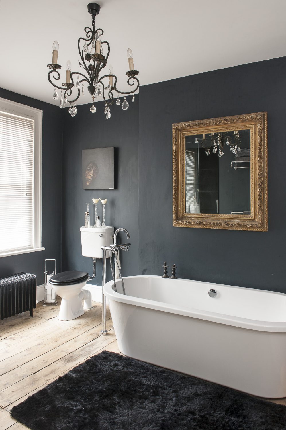 The juxtaposition of light and dark in this house is emphasised in the bathrooms. There are two good-sized rooms – one white and one black – both have a striking painting in a similar position; in the white bathroom there’s a picture of a skull by Ben Eine and in the black, a raw and intense painting by Alice Maylam titled ‘Out of the Dark’ which features a face protruding into the light and provided the inspiration for Rob’s bold colour choice...