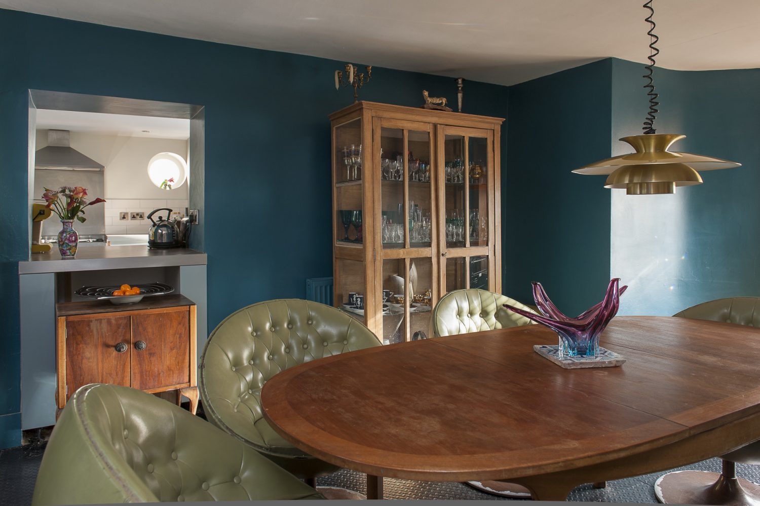 Nadene found the oval 60s teak dining table in a local charity shop and the couple have surrounded it with deep, green leather nightclub swivel chairs from eBay. A French glass-fronted and sided linen cabinet displays Nadene’s eclectic collection of glassware