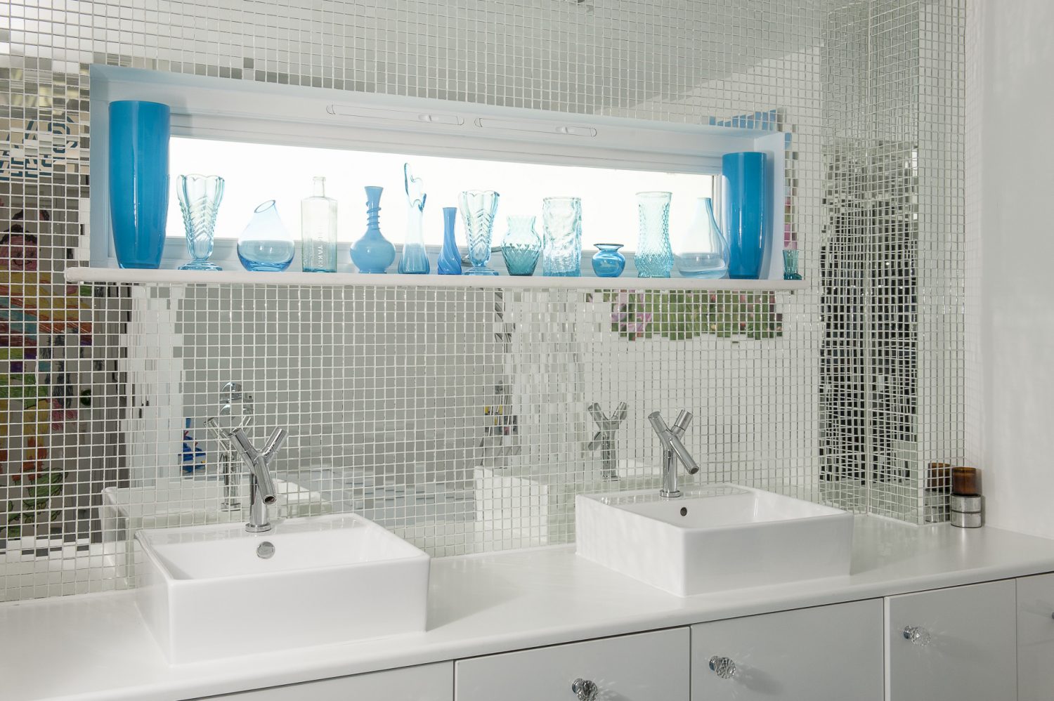 Like the downstairs loo, the rear wall of the family bathroom is tiled with mirrored mosaics